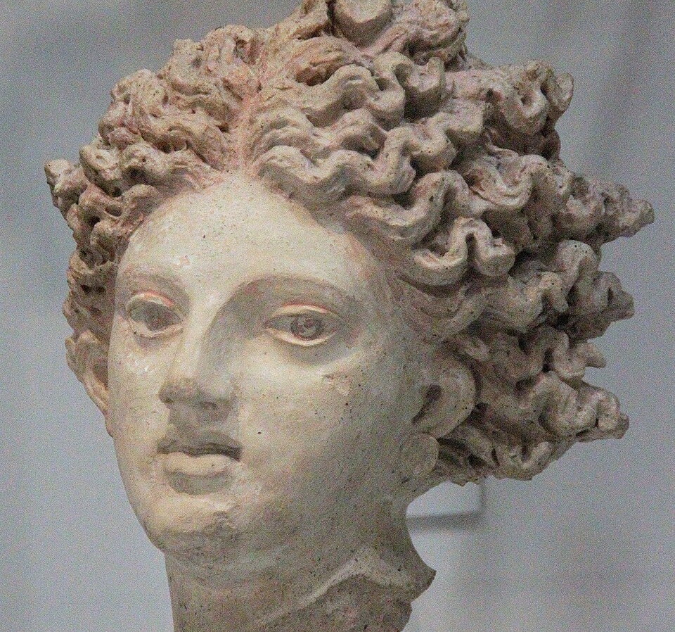 Detail of Leucothea, an Etruscan sculpture from Pyrgi, c. 350 BCE. The head only survives; she is looking at the observer with a slightly apprehensive expression. The lips are gently parted; the hair is thick and wavy.