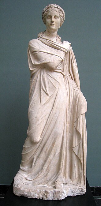 Marble statue of Polyhymnia from Monte Calvo, Italy, 2nd century CE. A crowned figure with a solemn face and long, flowing robes either stands or dances. Her right arm is crossed over her chest, the hand touching her left shoulder. The left hand gathers up the robe beside her.
